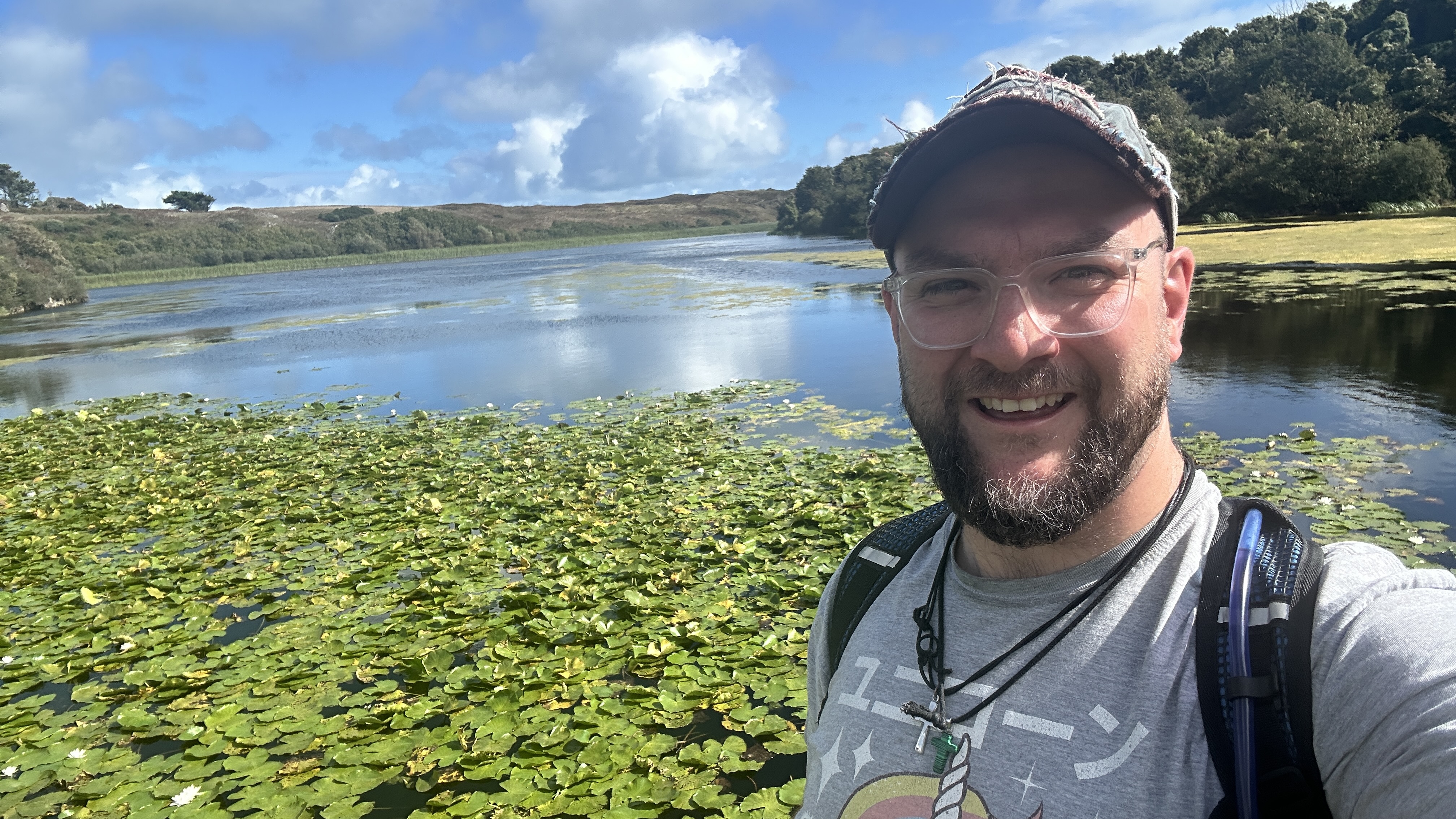 Joby Malkin on a walk beside a lake covered in lily pads.